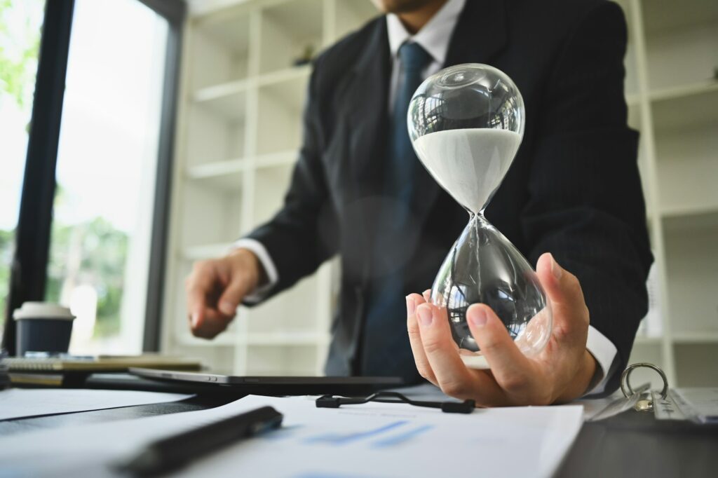 Hand of businessman holding hourglass. Business and time management concept