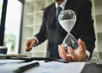 Hand of businessman holding hourglass. Business and time management concept