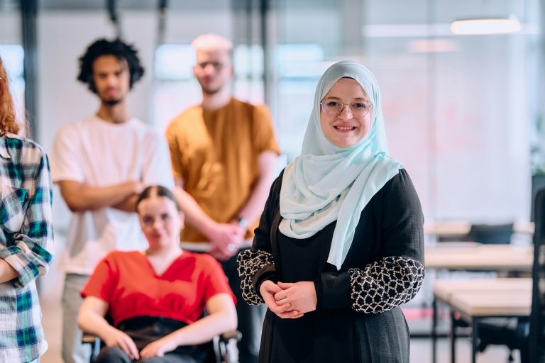 A diverse group of young business people walking a corridor in the glass-enclosed office of a modern