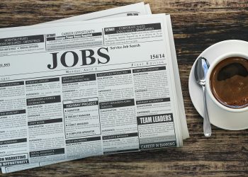 Job classifieds ads newspaper and coffee cup on wooden table. Job search concept.