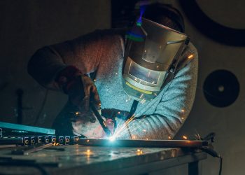 Man worker welding metal with welding machine in a factory or workshop