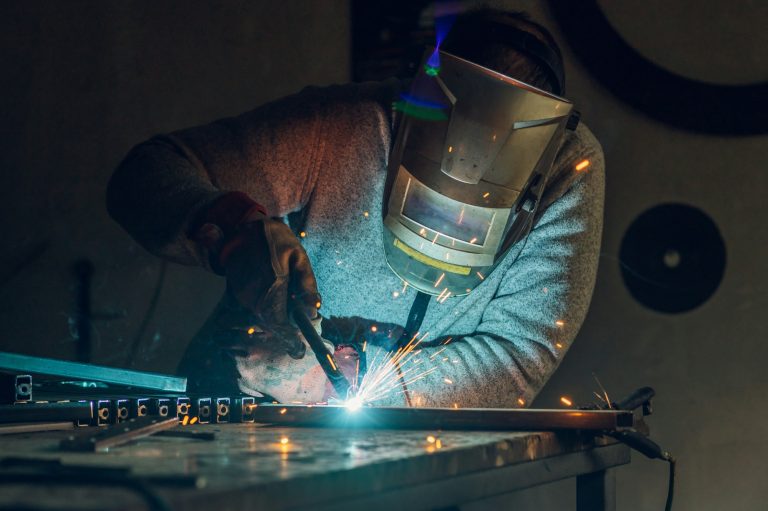 Man worker welding metal with welding machine in a factory or workshop