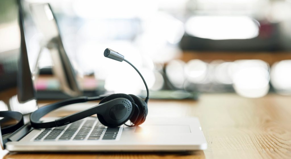 VOIP headset on desk with laptop computer at customer service. call center and helpline concept.