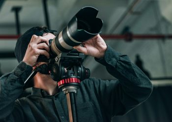 Low angle view of videographer with camera on tripod in photo studio