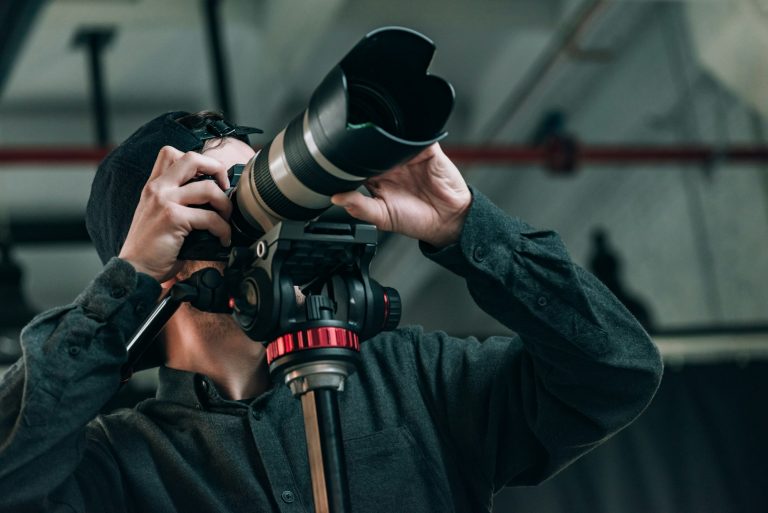 Low angle view of videographer with camera on tripod in photo studio