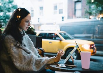 Freelance young woman typing on tablet in cafe
