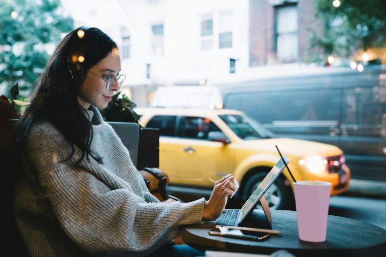 Freelance young woman typing on tablet in cafe