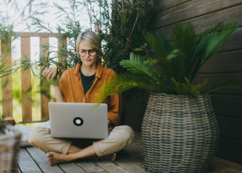 Woman working on laptop while eating sandwich. Businesswoman working remotely from outdoor