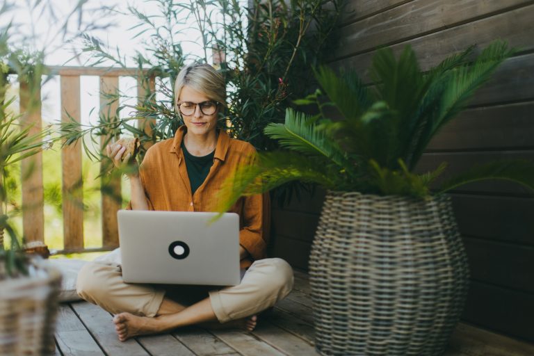 Woman working on laptop while eating sandwich. Businesswoman working remotely from outdoor