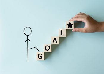 A man climbing to his goal of achievement, wooden blocks as stairs to the prize.