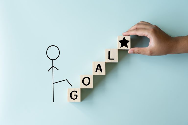 A man climbing to his goal of achievement, wooden blocks as stairs to the prize.