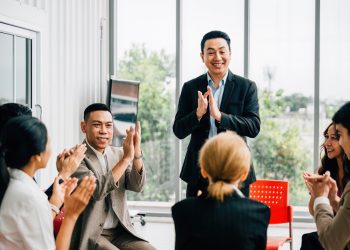 A seminar leader imparts wisdom to a diverse audience, and participants actively raise their hands