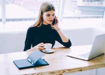 Administrative assistant having hot drink and talking on mobile phone