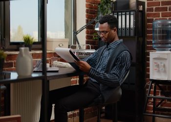 African american employee planning project with laptop and paperwork