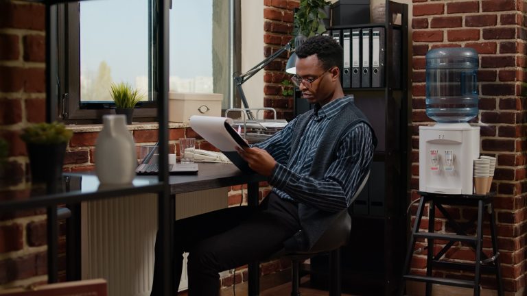 African american employee planning project with laptop and paperwork