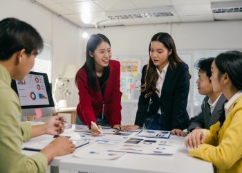 Asian business team analyzing charts and discussing marketing strategy