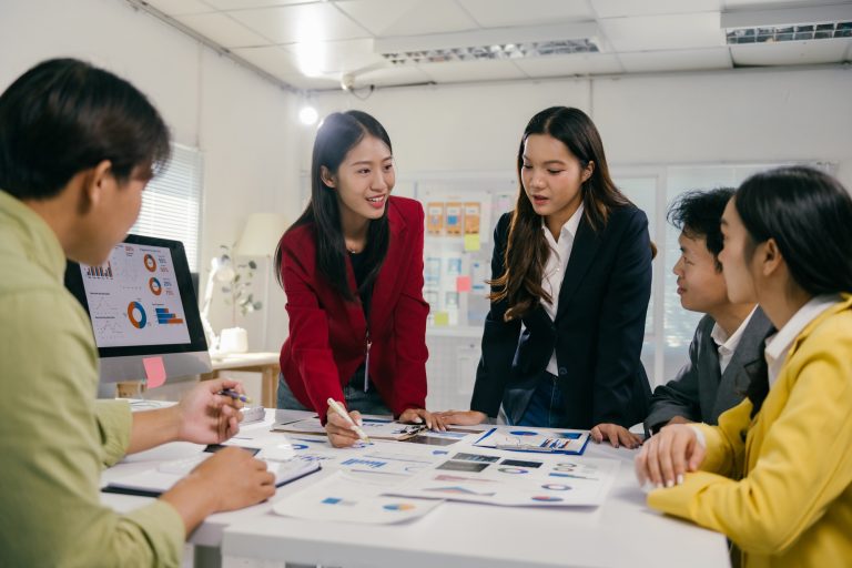 Asian business team analyzing charts and discussing marketing strategy