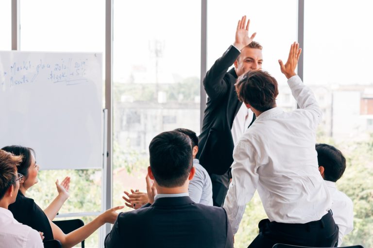 Boss giving high five to employee during conference