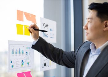 Business professional organizing sticky notes on office window