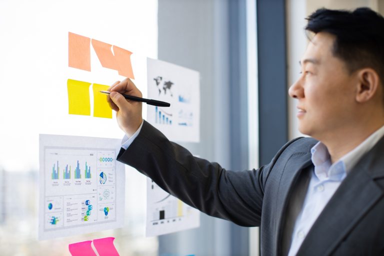 Business professional organizing sticky notes on office window