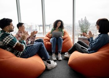 Businesswoman receiving applause from colleagues in office