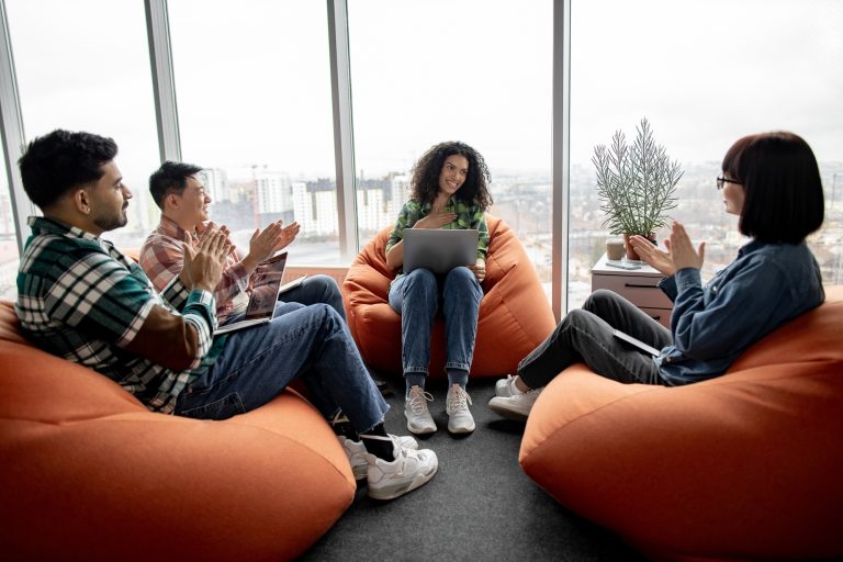 Businesswoman receiving applause from colleagues in office