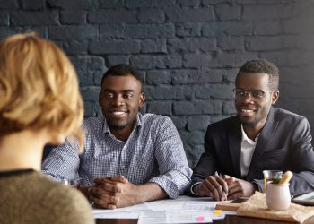 Caucasian female candidate being interviewed for position in office during job interview. Two Africa