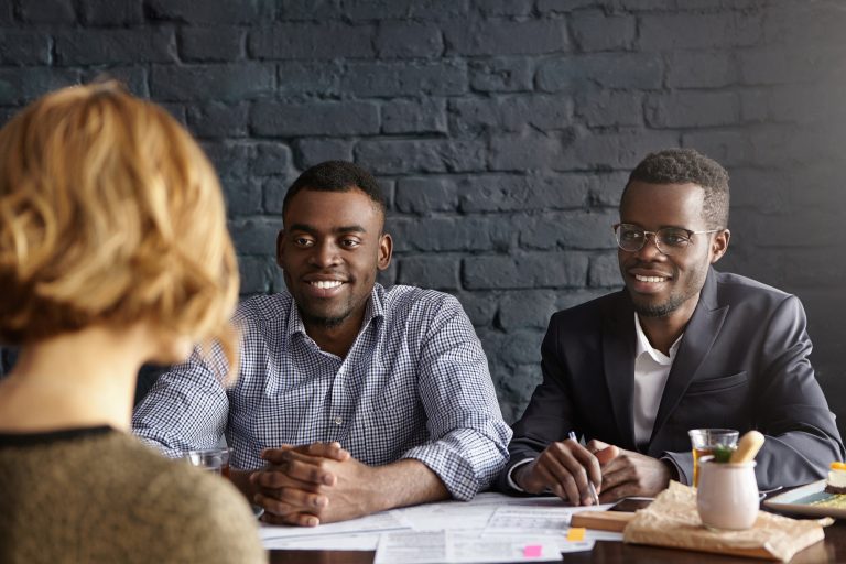 Caucasian female candidate being interviewed for position in office during job interview. Two Africa