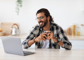 Cheerful indian guy looking for job online at home