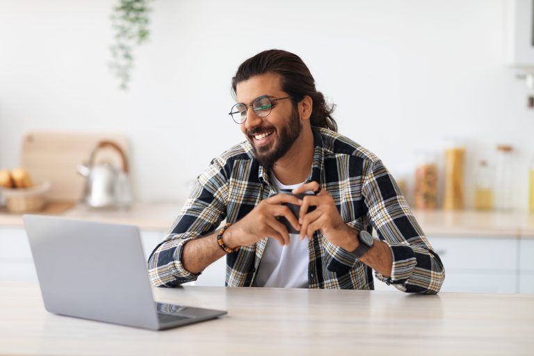 Cheerful indian guy looking for job online at home