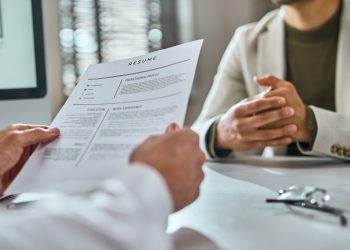 Close-up of businessman reading candidate's CV on a job interview.
