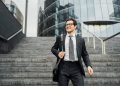 Confident businessman walking downstairs outside modern office building.
