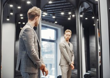 Handsome man with beard choosing jacket in a shop