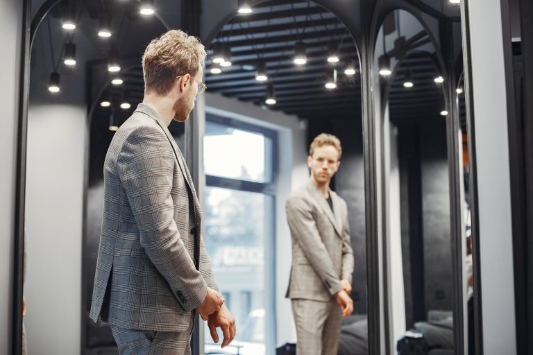 Handsome man with beard choosing jacket in a shop