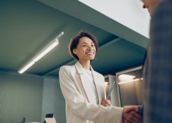 Happy young business woman sales manager handshaking greeting client in office