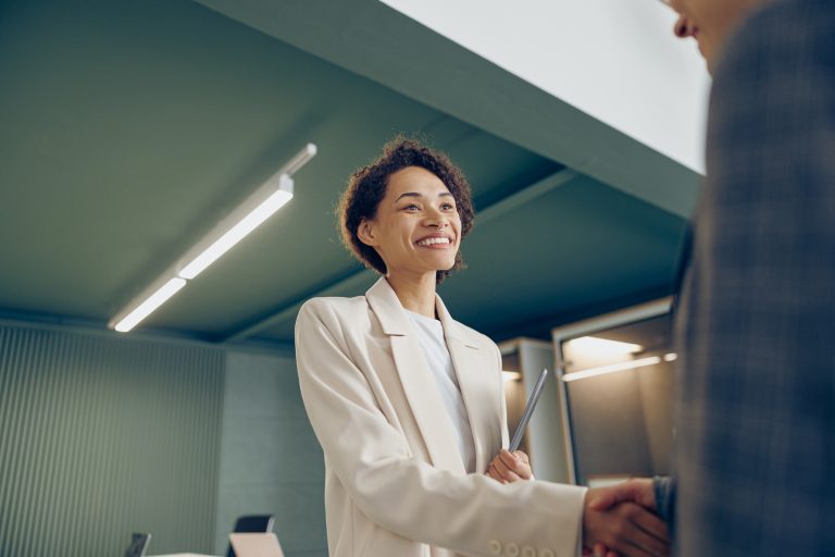 Happy young business woman sales manager handshaking greeting client in office