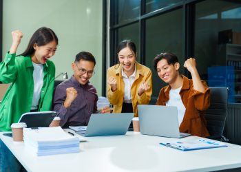 In a boardroom, an Asian team discusses startup financials and business terms.