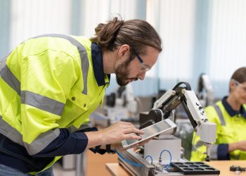 Male engineer using remote testing and control AI robot model in academy robotics laboratory room