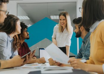 Pretty female team leader talking with mixed race group of people in the office