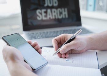 Remote job search at home. Man appoints interview for vacancy in mobile phone, types meeting date