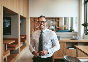 Smiling mature businessman standing alone in an office cafeteria