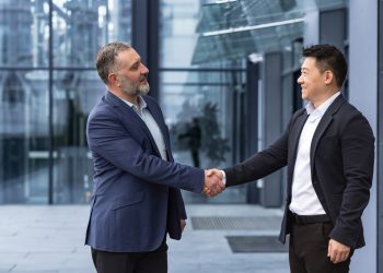 Two businessmen, bosses greet each other by shaking hands, a diverse group of men