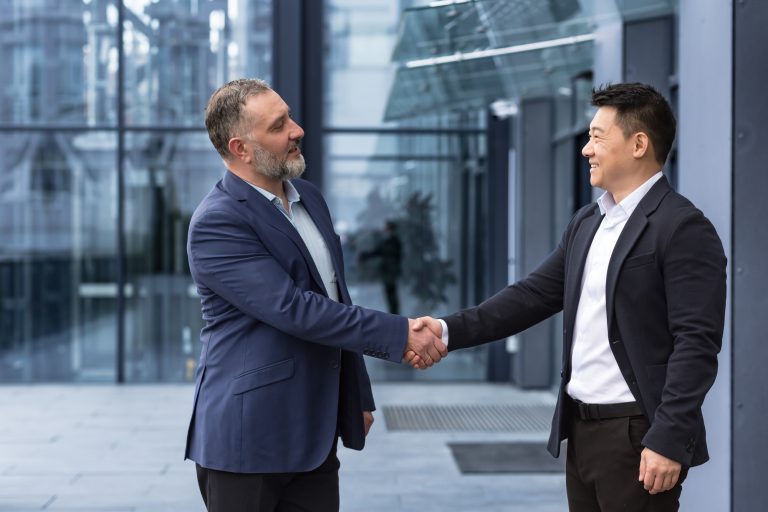 Two businessmen, bosses greet each other by shaking hands, a diverse group of men