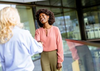 Warm Handshake and Laughter at a Professional Networking Event in a Modern Glass Building