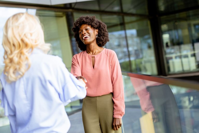 Warm Handshake and Laughter at a Professional Networking Event in a Modern Glass Building