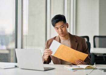 Young Asian professional business man receiving business mail letter in office.