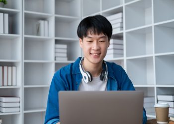 Portrait of young adorable college student working on his project with laptop computer in the study