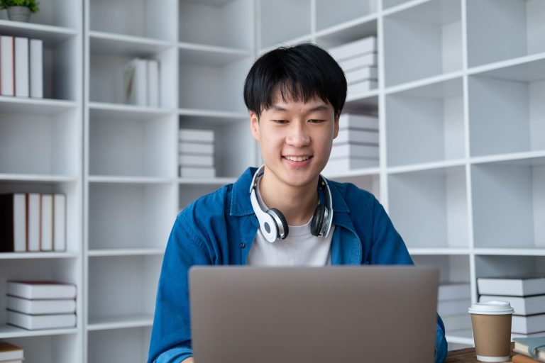 Portrait of young adorable college student working on his project with laptop computer in the study