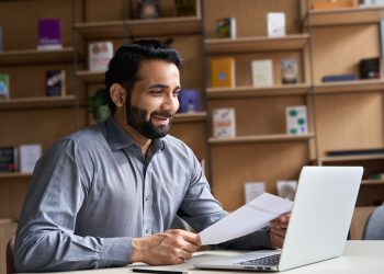 Smiling indian business man holding cv document having virtual job interview.