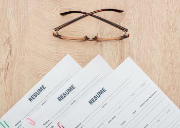 top view of resume templates and glasses on wooden surface